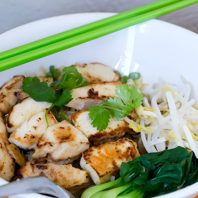 Ninethai Kitchen's chicken noodle bowl with bok choy, bean sprouts, and cilantro, with green chopsticks.